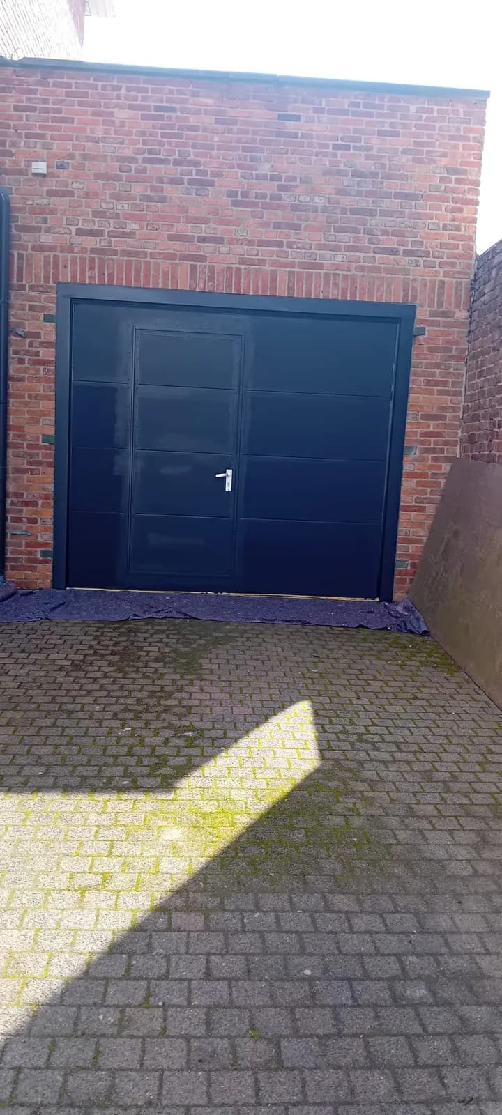 Garagepoort geschilderd in marineblauw met zwart kader